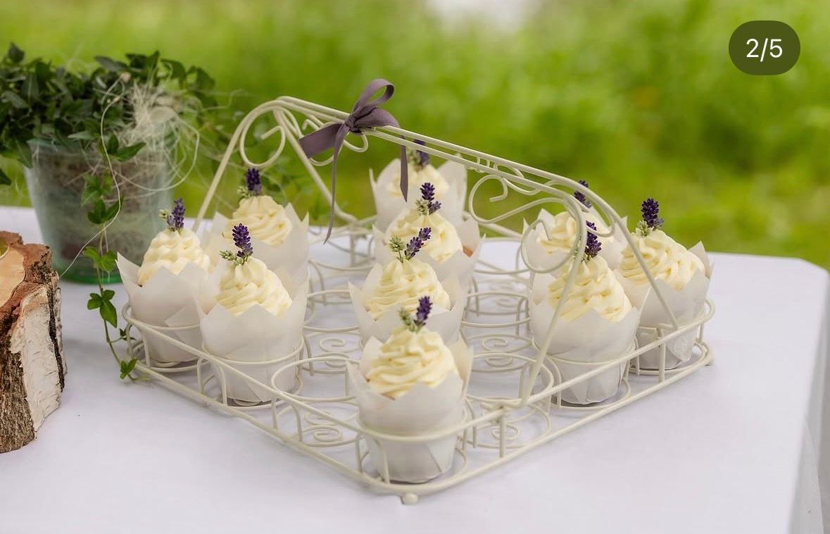 Kleine Cupcakes mit weißer Creme und Lavendel auf einem weißen Metalltablett im Freien.