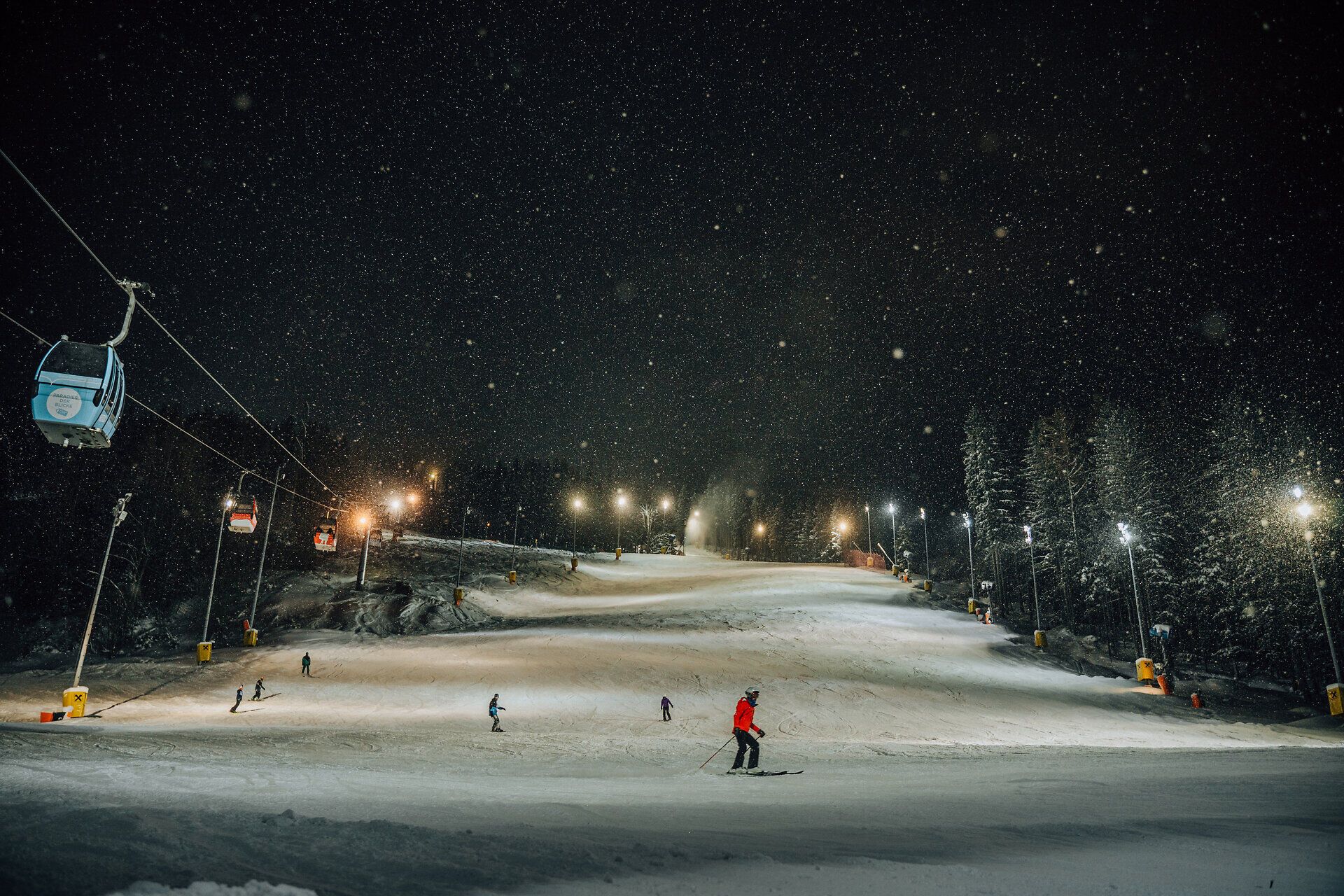 Nächtlich beleuchtete Skipiste mit Skifahrern am Semmering Hirschenkogel.