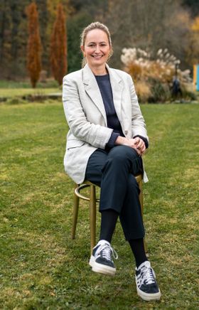 Tessa Erker-Tegetthoff, intendantin des Fabelhaft Festivals, sitzt auf einem goldenen Sessel auf einer grünen Wiese.