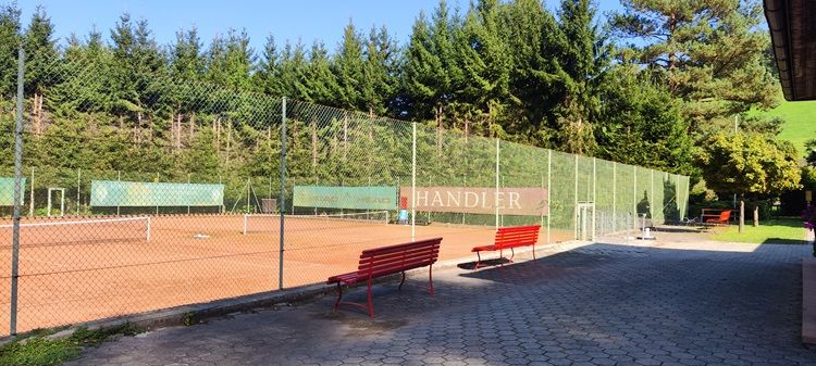 Tennisplatz mit rotem Sand und Bänken in Bad Schönau.