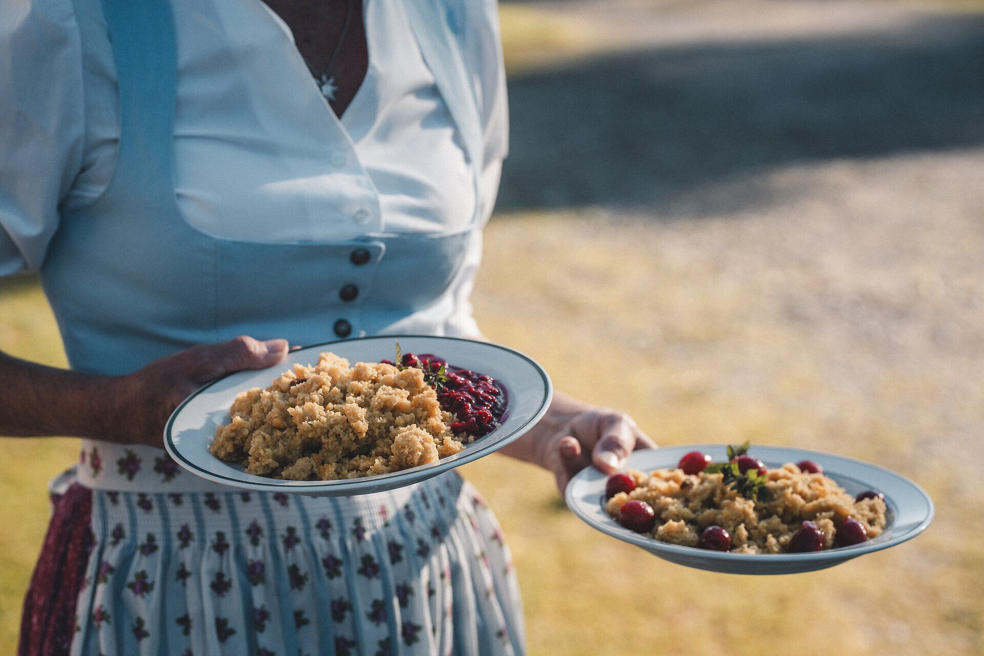 Frau in traditioneller Kleidung serviert Süßspeisen.