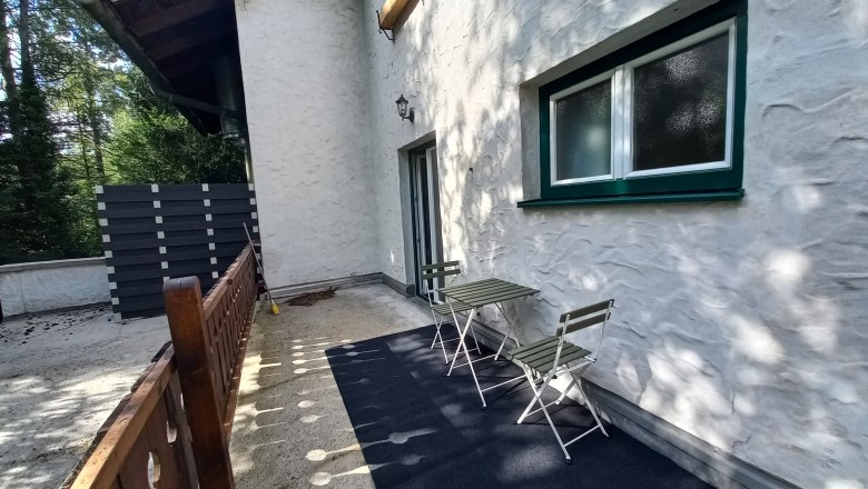 Ferienwohnung Detox, © Dekic-Ouaja Terrasse einer Ferienwohnung mit Tisch und Stühlen, umgeben von Bäumen.