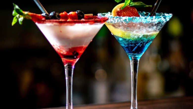 Zwei bunte Cocktails in Martini-Gl&auml;sern mit Beeren und Minze dekoriert.