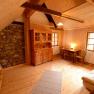 Cozy room with wooden walls, two beds, table and chairs, wardrobe and stone wall.