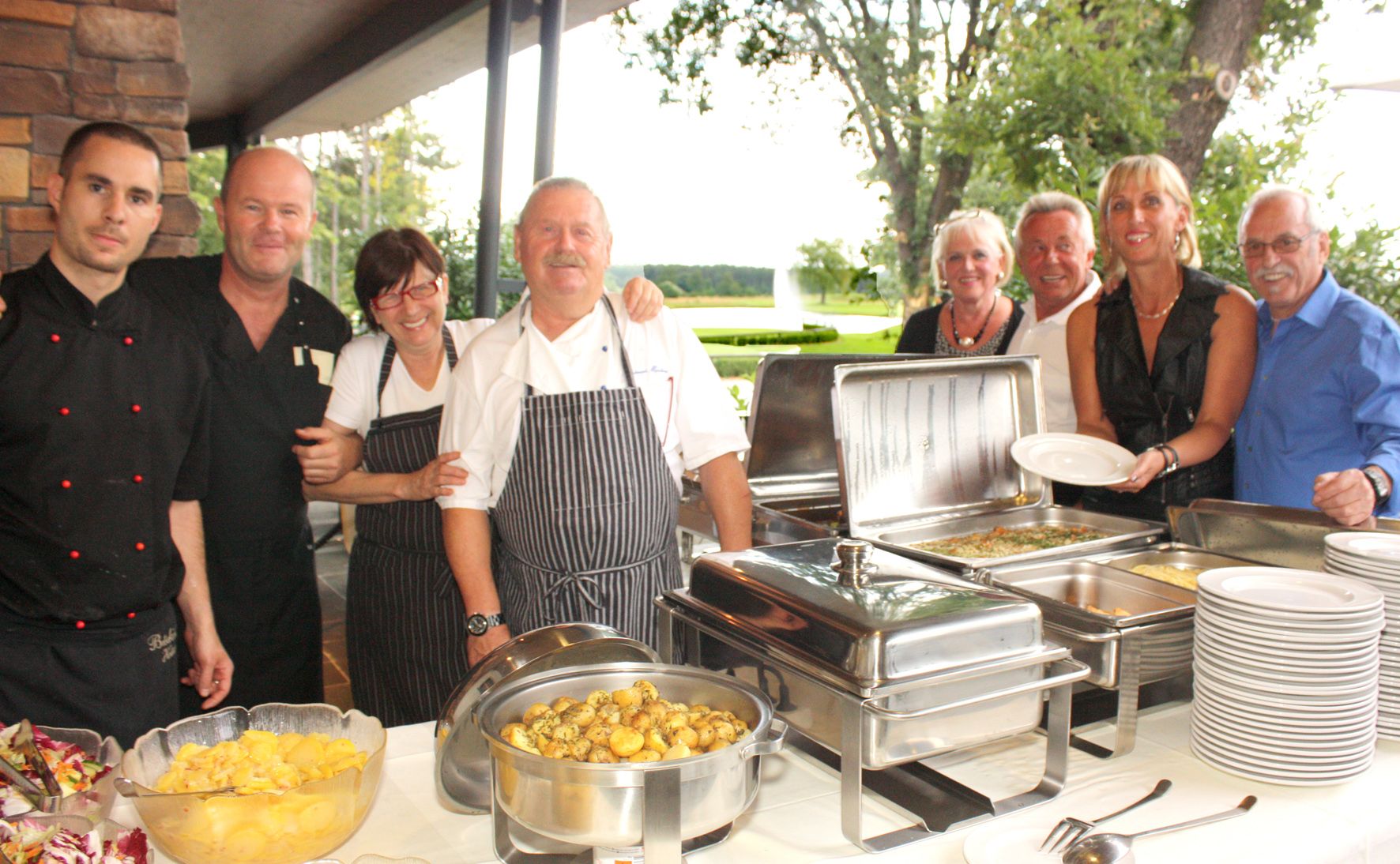 Gruppe von Menschen in einem Restaurant neben einem Buffet mit Speisen.