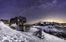 Mountain hut in the snow under a clear starry sky.