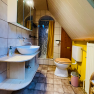 Kleines Badezimmer mit Waschbecken, Toilette und Dusche unter einer Dachschräge.