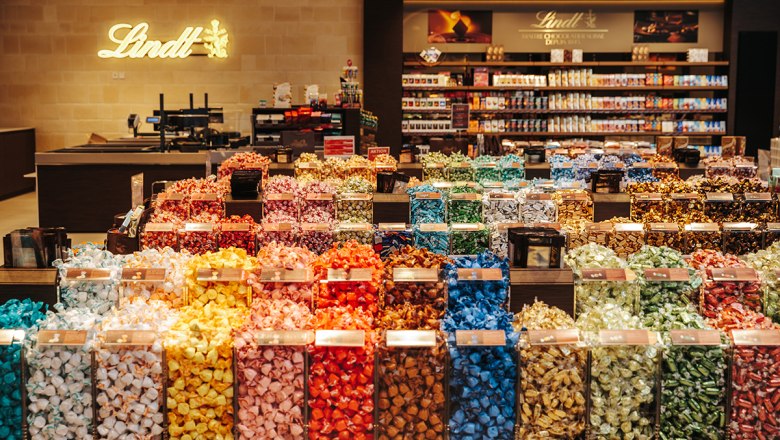 Ein Geschäft mit einer großen Auswahl an bunten Lindt-Pralinen in durchsichtigen Behältern.