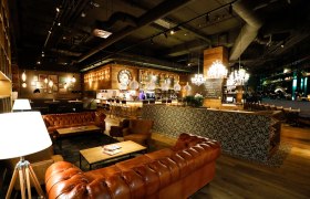 Elegantes Restaurant mit Ledersofas, Holzmöbeln und Kronleuchtern.