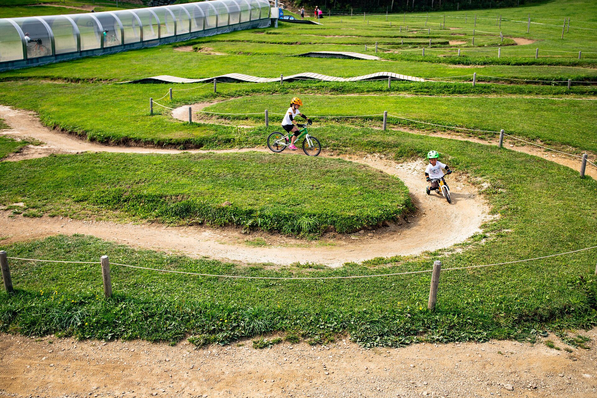 Inmitten der sanften Hügel der Wiener Alpen gleiten begeisterte Mountainbiker über kurvenreiche Trails, umgeben von üppigem Grün und der frischen Bergluft. Der Mini Bikepark bietet ein aufregendes Erlebnis für Groß und Klein, während die Sonne über der malerischen Landschaft strahlt.
