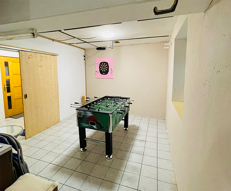 A games room with a table football table and a dartboard on the wall.