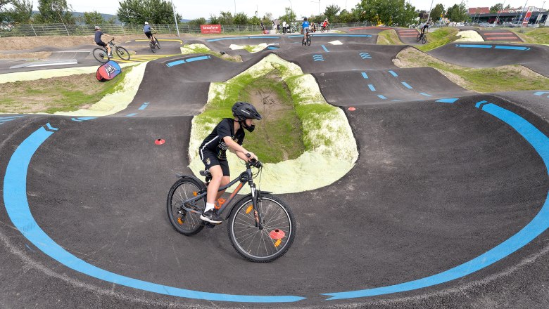 Ein Fahrradfahrer mit schwarzem Helm auf einer Pumptrack-Strecke in Wiener Neustadt.
