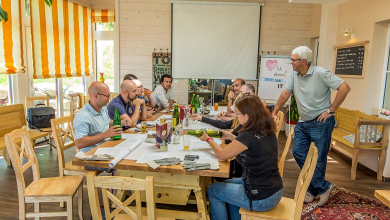 People at a seminar in a cozy room with wooden furniture and a projector.