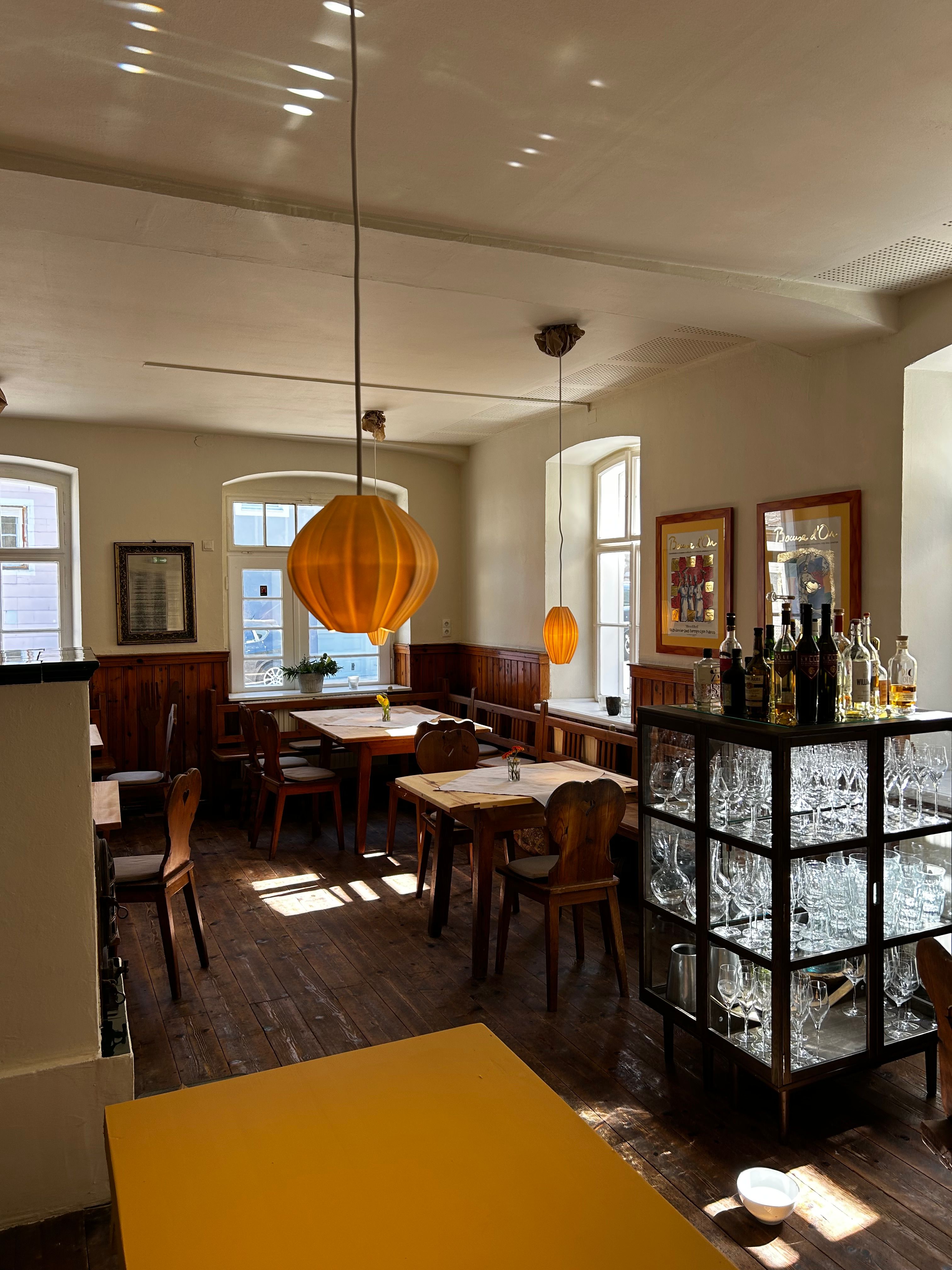 Interior view of a traditional inn with wooden furniture and orange lamps.