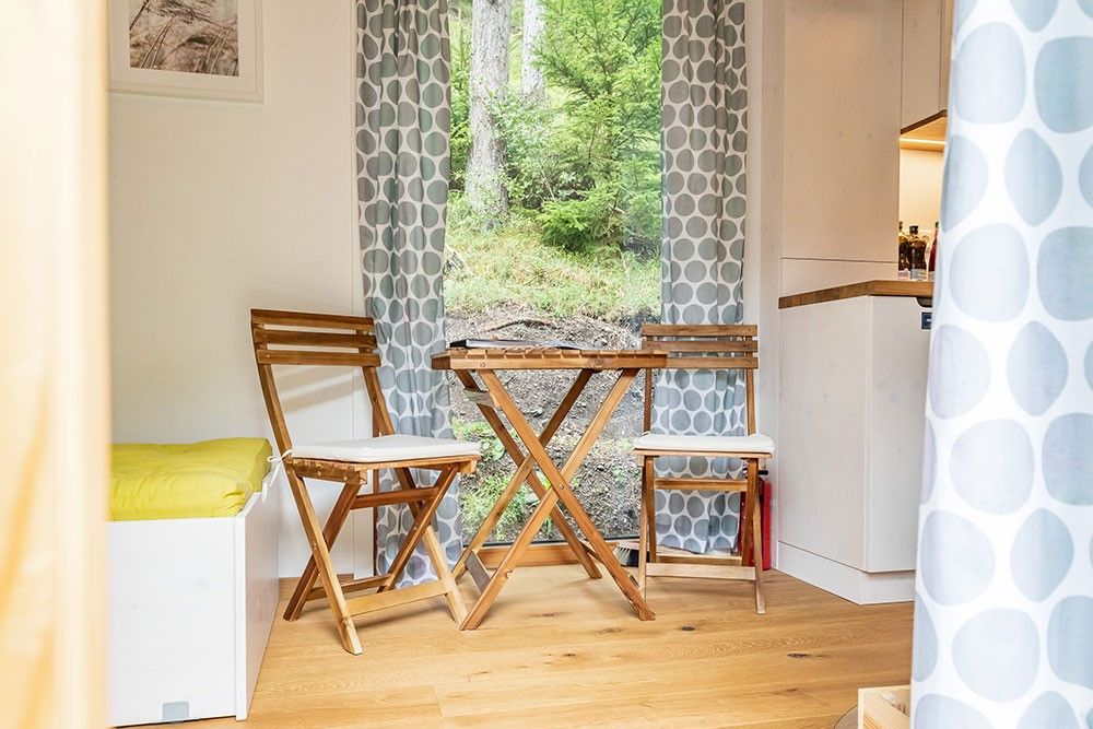 Gemütlicher Sitzbereich mit Holzmöbeln und Blick ins Grüne.