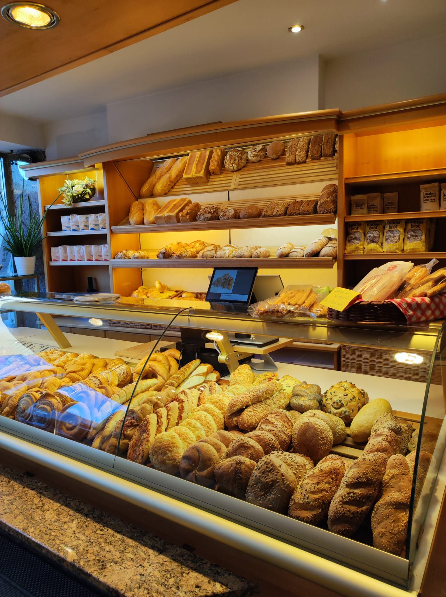 Innenansicht von Cafe Dietmayer in Ternitz mit einer gut gefüllten Bäckerei-Theke voller Brot, Gebäck und Brötchen.