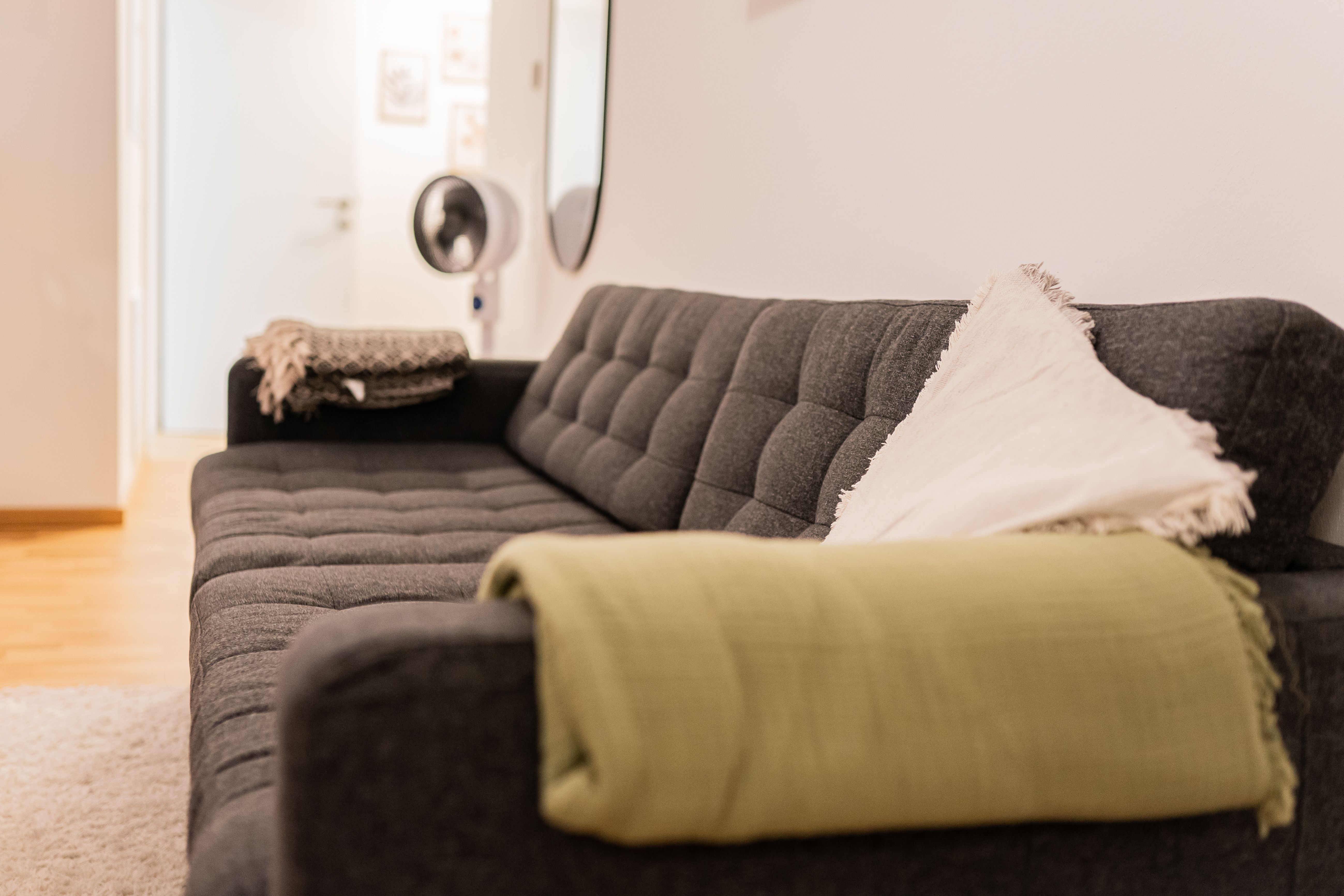 Graues Sofa mit grüner Decke