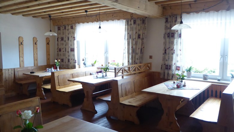 Gemütliches Gastzimmer mit Holzmöbeln und Blumen auf den Tischen.