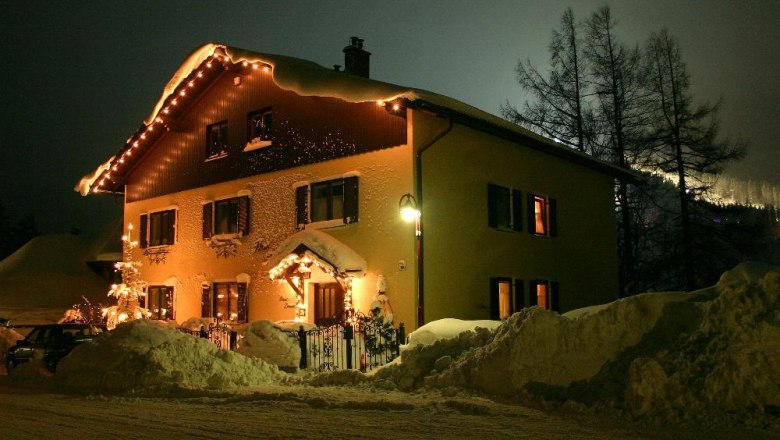 House Kohl in winter, © Tourismusbüro Semmering An illuminated house in the snow at night, surrounded by high piles of snow.