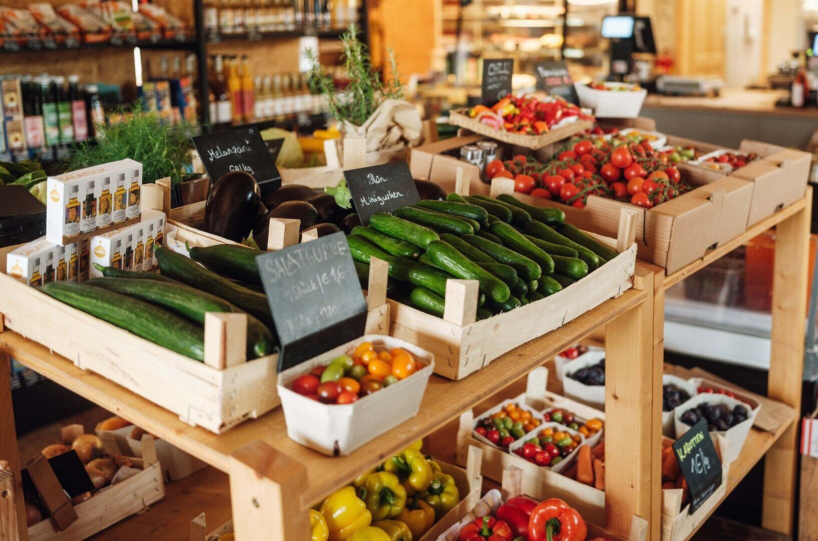 Ein einladender Bauernmarkt präsentiert frisches Gemüse und Obst in bunten Holzkisten. Die Atmosphäre ist lebhaft und einladend, während die Besucher die regionalen Köstlichkeiten entdecken und genießen.
