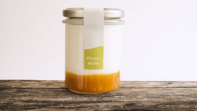 Ein Glas gefüllt mit Naturjoghurt und Fruchtspiegel auf einem Holztisch.