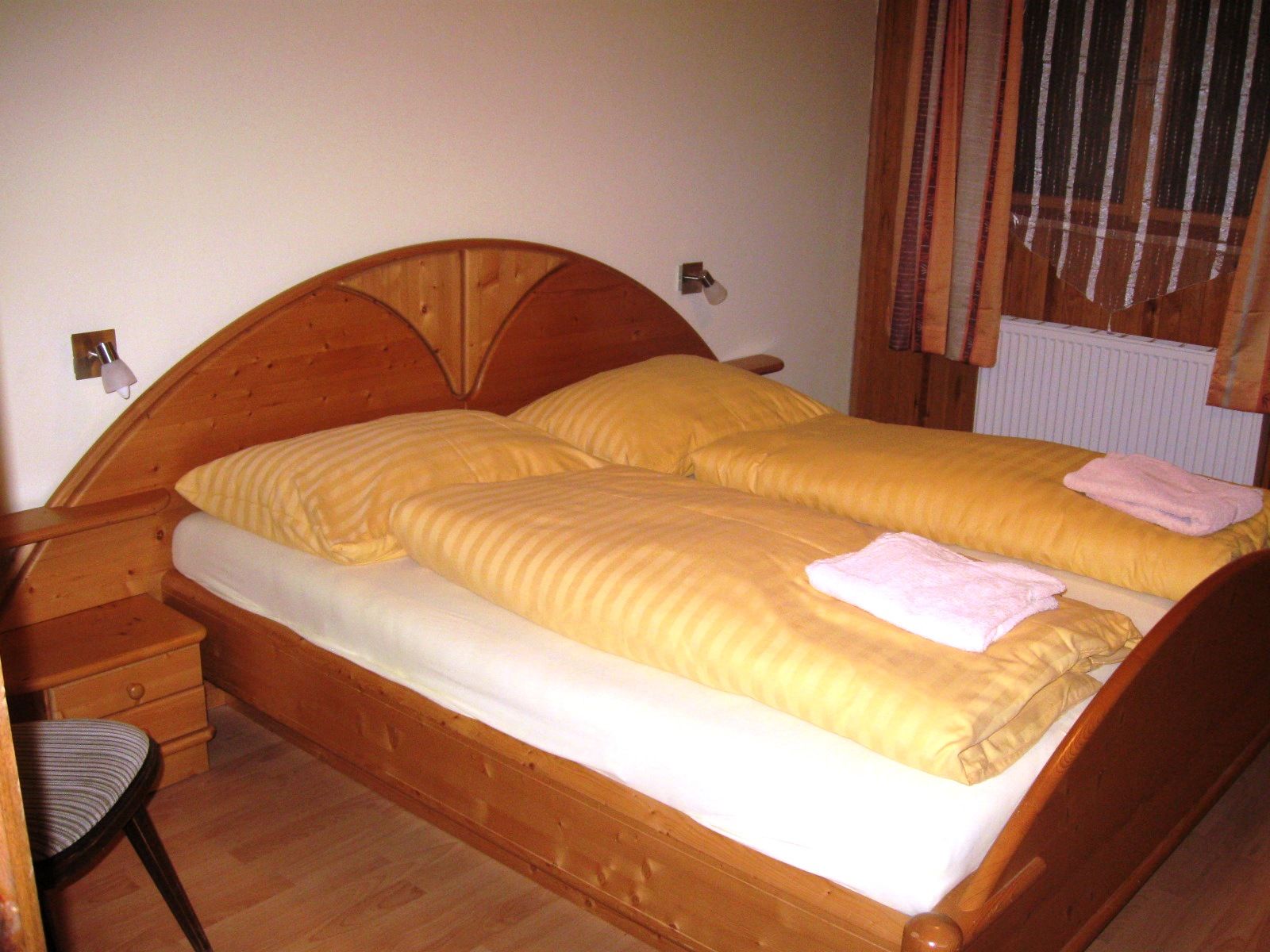 Holzbett mit gelber Bettwäsche in einem Zimmer.