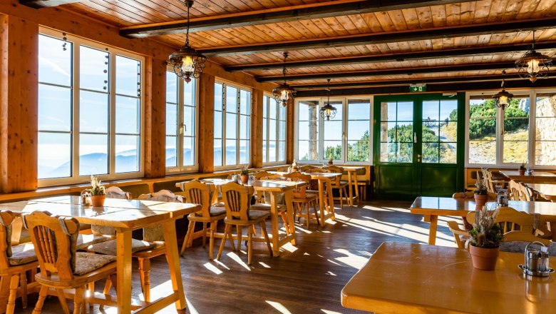 Cozy guest lounge with wooden furniture and large windows offering a view of the mountains.