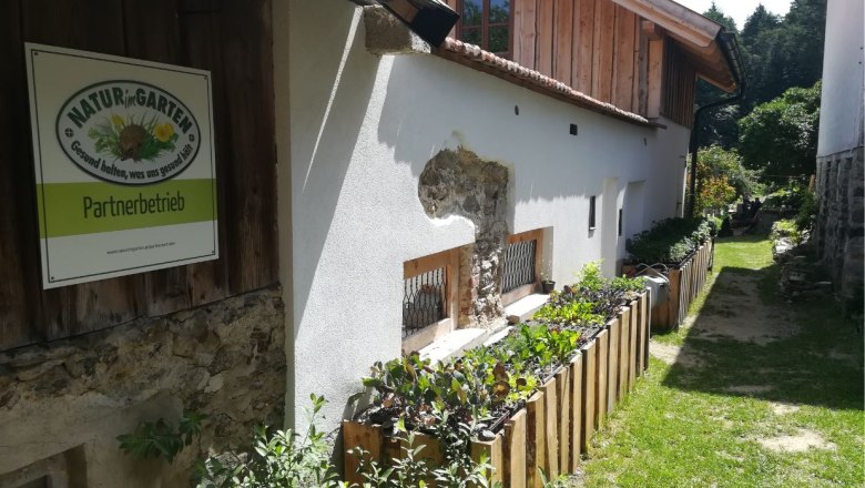 Außenansicht eines Gebäudes mit Schild 'Natur im Garten Partnerbetrieb'.