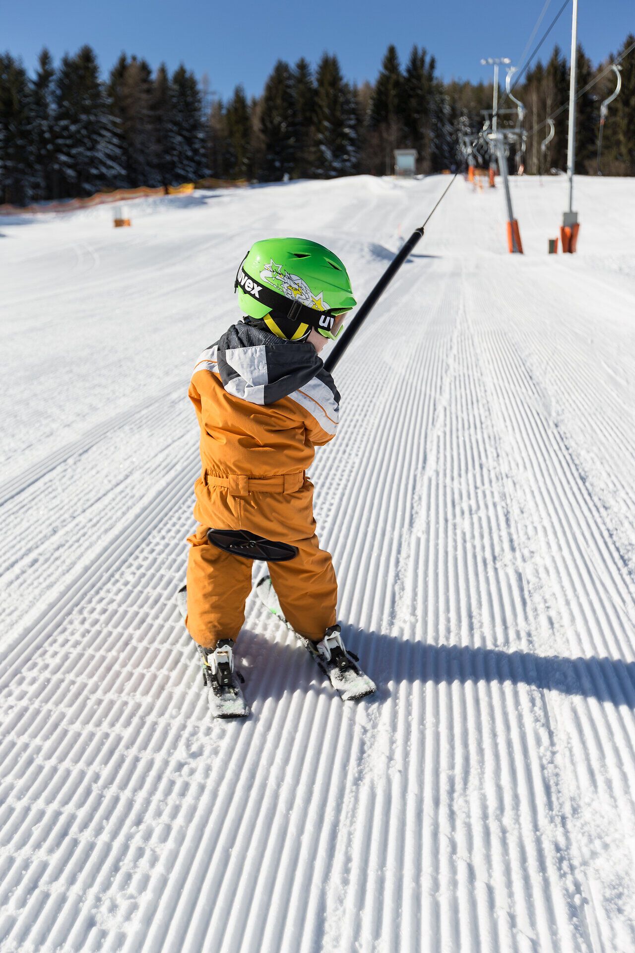 Ein kleiner Skifahrer genießt die frische Bergluft und die strahlende Sonne, während er sich auf den nächsten Schwung vorbereitet. Die perfekt präparierte Piste lädt zu aufregenden Abfahrten ein und verspricht unvergessliche Momente im Schnee.