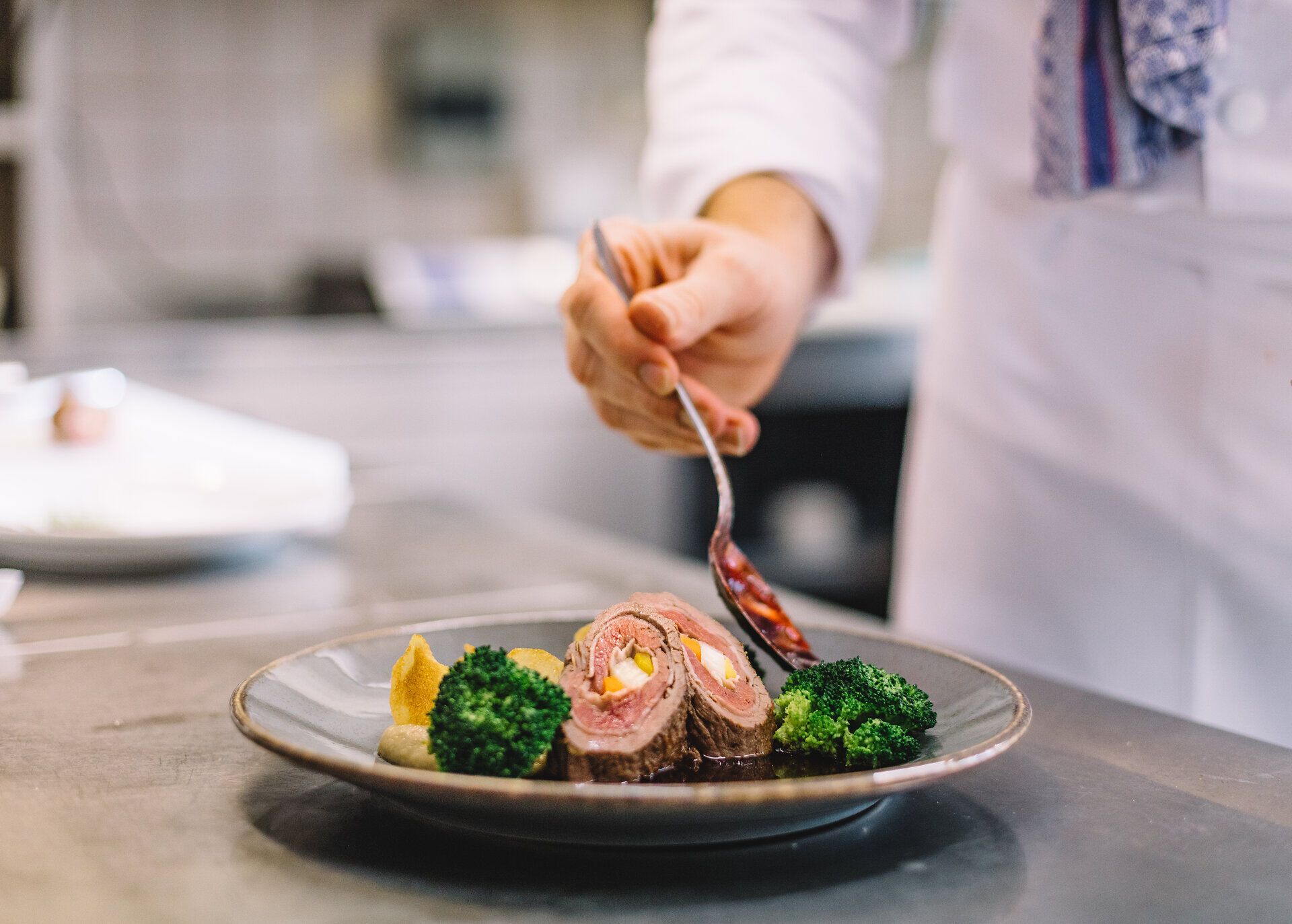 Ein kunstvoll angerichteter Teller mit zartem Rinderfilet und frischem Brokkoli lädt zum Genießen ein. Die harmonische Kombination aus Farben und Aromen verspricht ein unvergessliches Geschmackserlebnis in der idyllischen Umgebung der Wirtshauskultur.