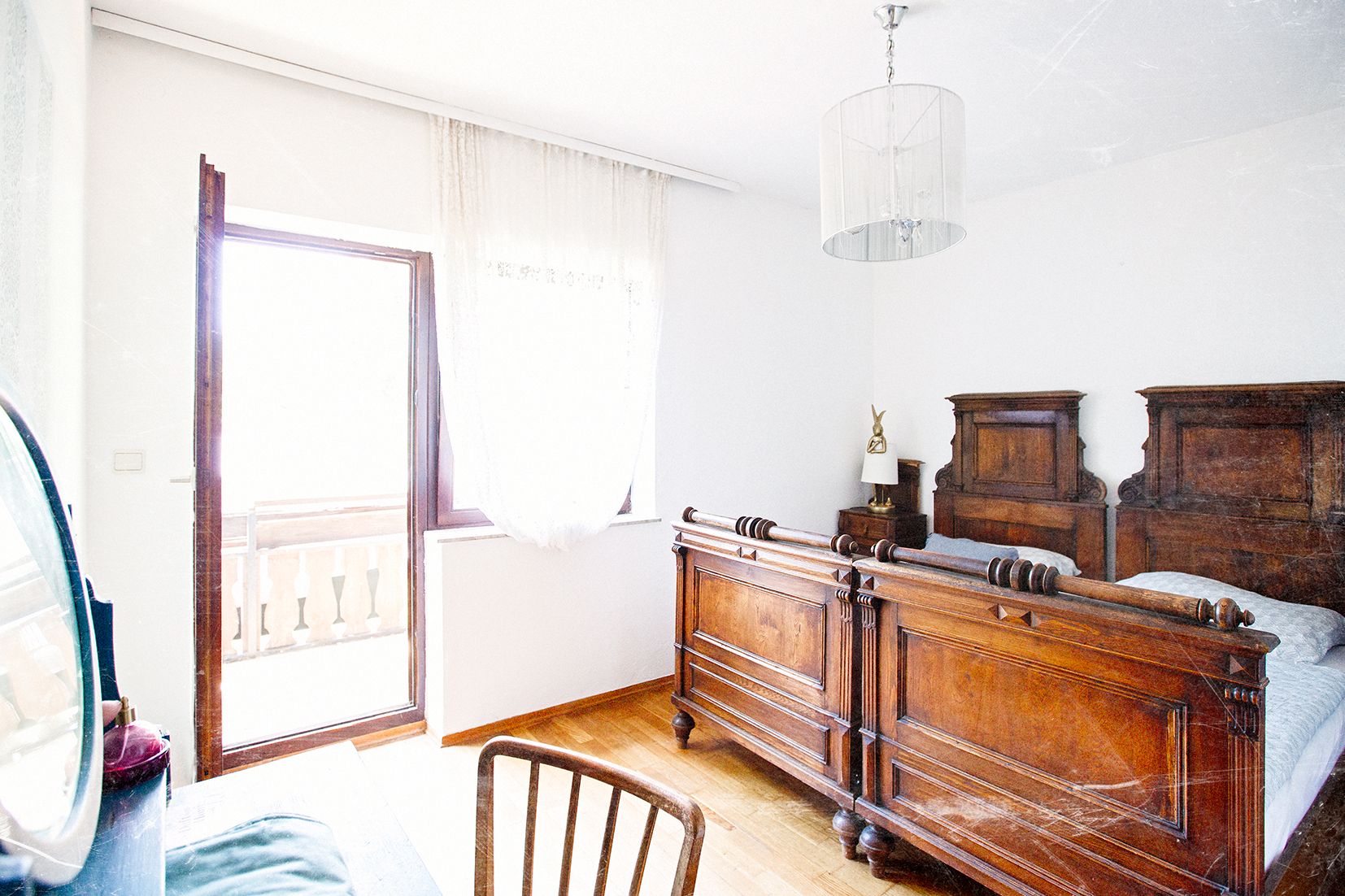 Helles Schlafzimmer mit antiken Holzmöbeln und einem Balkonzugang.