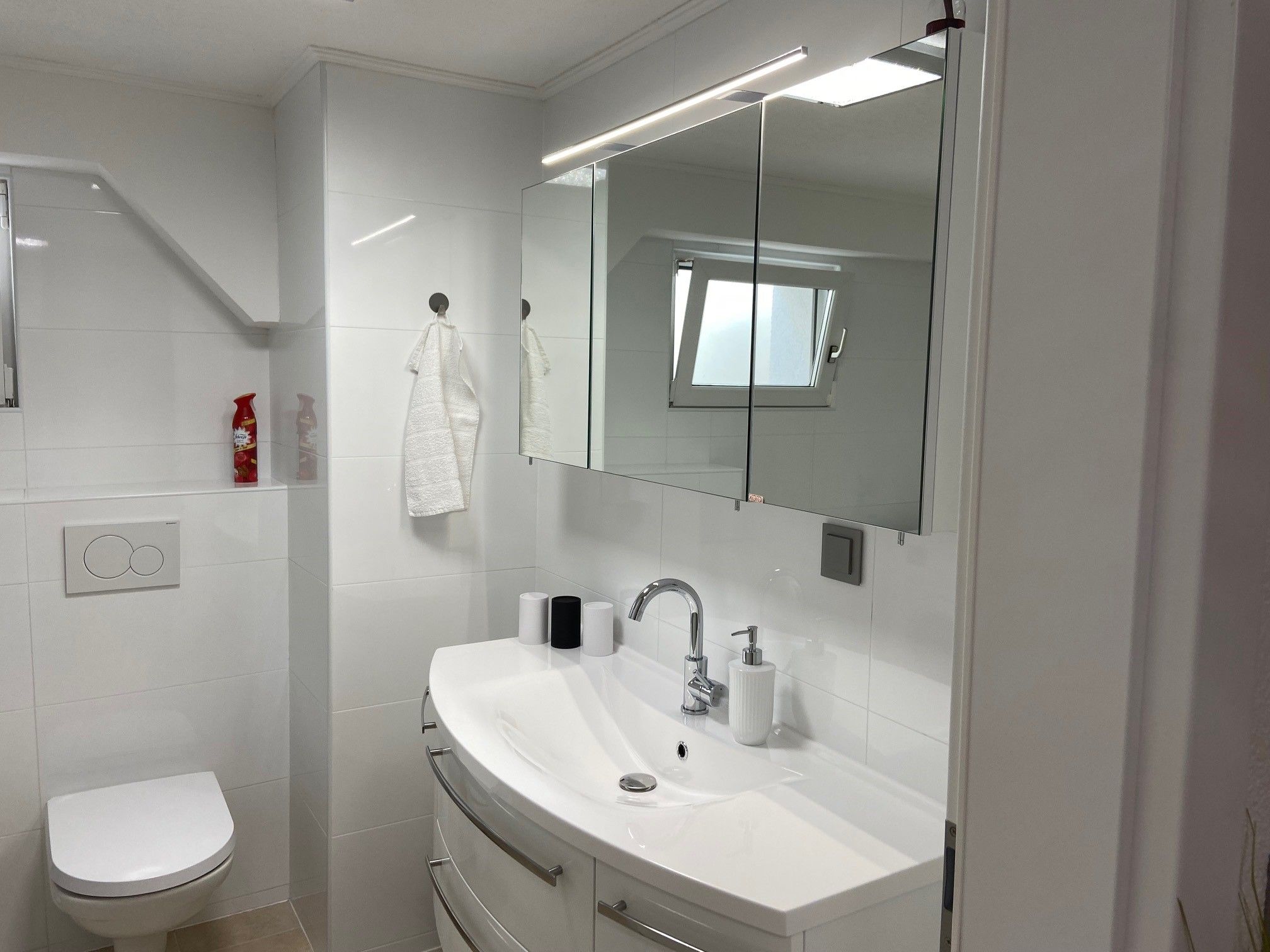 Modernes Badezimmer mit Waschbecken, Spiegel, Toilette und kleinem Fenster.