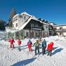 Winter scene with Alpengasthof Enzian and skiers in the snow.