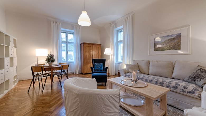 Gemütliches Wohnzimmer mit Sofa, Sessel, Esstisch und Regalen.