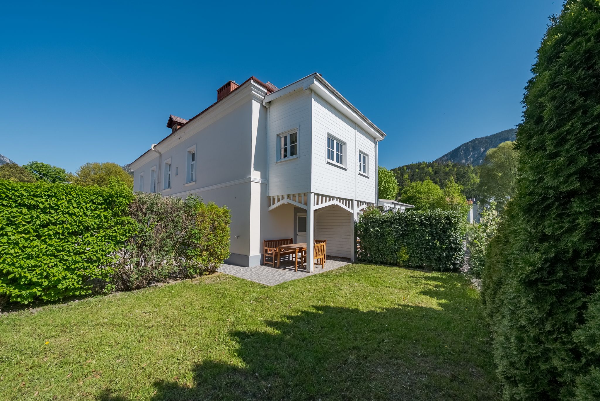 Ein weißes Gebäude mit Garten und blauen Himmel im Hintergrund.
