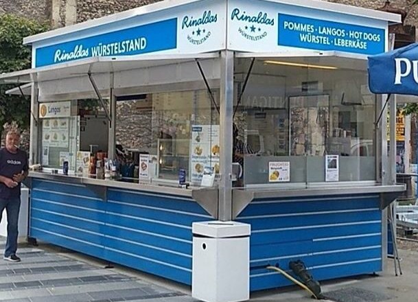 Ein blauer Imbissstand namens Rinaldas Würstelstand mit Angeboten wie Pommes und Hot Dogs.