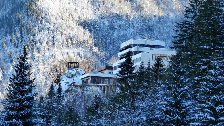 Winterliche Ansicht des Sporthotels Semmering umgeben von schneebedeckten Bäumen und Bergen.