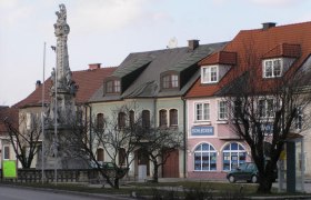 Stra&szlig;enszene in Ebenfurth mit historischen Geb&auml;uden und einer Statue.