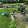 Garden with sun lounger, pond and plants.