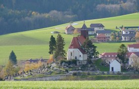 Erasmuskirche in Krumbach mit umliegendem Friedhof und grüner Landschaft.