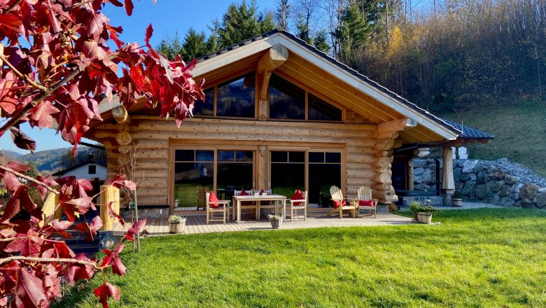 RaxChalet, © Wiener Alpen Holzchalet mit Terrasse und roten Herbstblättern im Vordergrund.