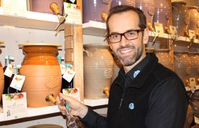 Ein Mann füllt eine Flasche aus einem großen Keramikfass bei Vom Fass.