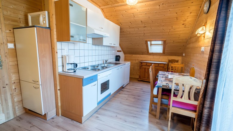 K&uuml;che mit Holzverkleidung, Esstisch und K&uuml;chenzeile.